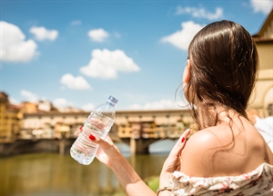 A woman holding a water bottle to help stay hydrated during a heatwave