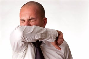 Man with allergies sneezing into his elbow